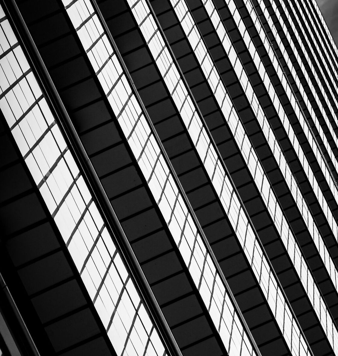 Low-angle shot of a modern skyscraper in monochrome, highlighting geometric lines.